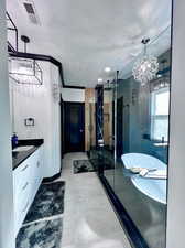 Bathroom featuring vanity, a notable chandelier, crown molding, independent shower and bath, and a textured ceiling