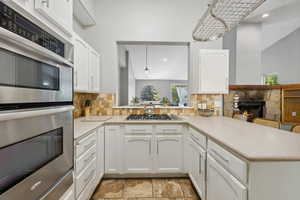 Kitchen with stainless steel appliances, kitchen peninsula, decorative light fixtures, and a fireplace