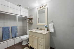 Full bathroom with washtub / shower combination, tile patterned flooring, vanity, and toilet