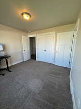 Unfurnished bedroom featuring dark carpet