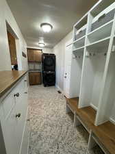 Mudroom with stacked washer and dryer and sink