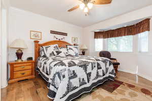 Bedroom featuring ornamental molding, light wood-type flooring, and ceiling fan