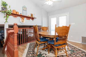 Dining area featuring ceiling fan, hardwood / wood-style floors, and vaulted ceiling