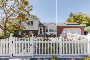 View of front facade featuring solar panels and a garage