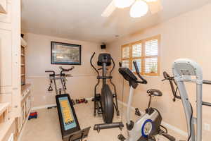 Workout area with ceiling fan and light colored carpet