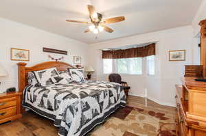 Bedroom featuring ceiling fan, ornamental molding, and wood-type flooring