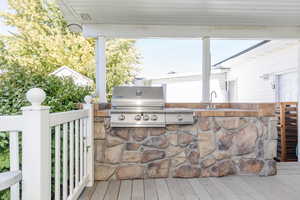 View of patio / terrace featuring grilling area, a wooden deck, sink, and exterior kitchen