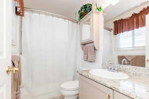 Bathroom with a shower with shower curtain, vanity, and toilet