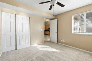 Unfurnished bedroom with light colored carpet and ceiling fan