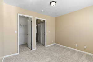 Unfurnished bedroom featuring a spacious closet, a closet, and light colored carpet