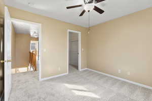 Unfurnished bedroom with light colored carpet, ceiling fan, a closet, and a walk in closet