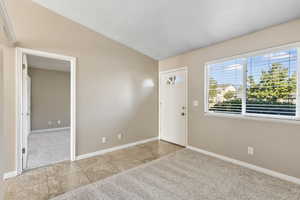 Entrance foyer with vaulted ceiling and light carpet