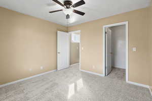 Unfurnished bedroom with ceiling fan, light carpet, and a walk in closet