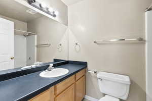 Bathroom featuring vanity, walk in shower, and toilet