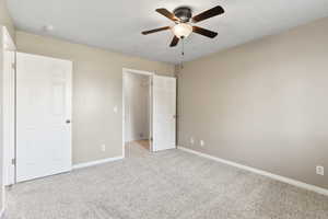 Unfurnished bedroom featuring light carpet, ceiling fan, a closet, and a walk in closet