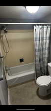 Bathroom with toilet and shower / bathtub combination with curtain