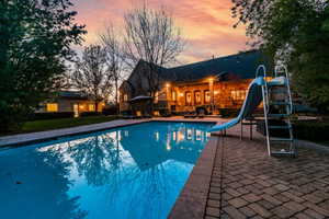 Pool at dusk with a water slide and a patio