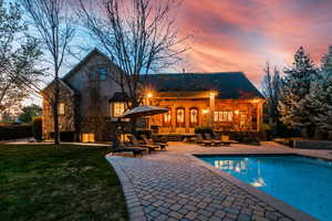 Back house at dusk with french doors, a patio, and a yard