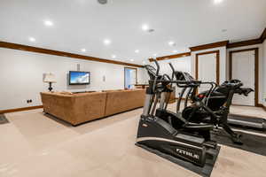 Workout area with ornamental molding and light colored carpet