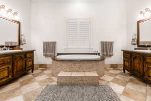 Bathroom with crown molding, a relaxing tiled tub, and vanity