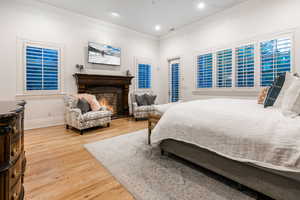 Bedroom with wood-type flooring, ornamental molding, and access to exterior