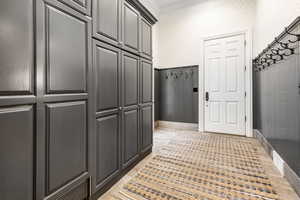 Mudroom with light hardwood / wood-style floors and crown molding