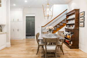 Dining area with light wood-type flooring and an inviting chandelier