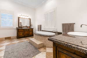 Bathroom with a relaxing tiled tub, vanity, tile patterned flooring, and ornamental molding