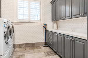 Clothes washing area featuring cabinets and washing machine and dryer