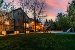 Back house at dusk with a yard and a patio area