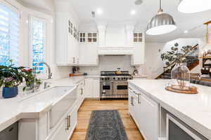 Kitchen featuring premium range, decorative light fixtures, light stone counters, and white cabinetry