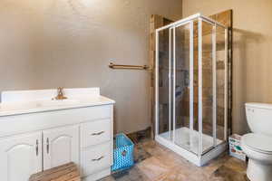 Bathroom featuring walk in shower, vanity, and toilet