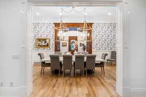 Dining space featuring an inviting chandelier, ornamental molding, and hardwood / wood-style flooring