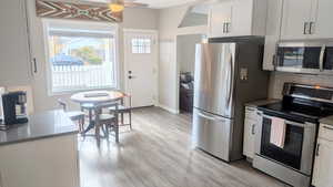 Kitchen featuring white cabinets, ceiling fan, light hardwood / wood-style floors, and appliances with stainless steel finishes