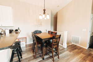 Dining area with wood-type flooring, lofted ceiling, and a chandelier