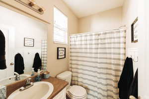 Bathroom with curtained shower, vanity, and toilet