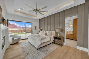 Bedroom with access to exterior, light hardwood / wood-style flooring, and a raised ceiling