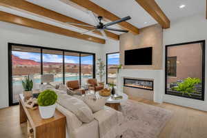 Living room with beamed ceiling, ceiling fan, and light hardwood / wood-style flooring