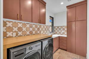 Laundry area with washing machine and dryer, cabinets, and light tile patterned flooring