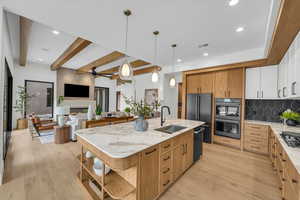 Kitchen with sink, white cabinetry, pendant lighting, a kitchen island with sink, and black appliances