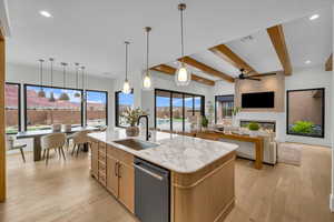 Kitchen with dishwasher, an island with sink, sink, hanging light fixtures, and light hardwood / wood-style floors