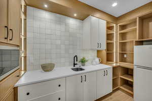 Kitchen with sink, white cabinetry, tasteful backsplash, light hardwood / wood-style flooring, and white refrigerator