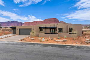 Pueblo-style home with a garage and a mountain view