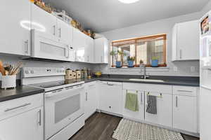 Kitchen featuring white appliances, dark hardwood / wood-style floors, sink, and white cabinetry