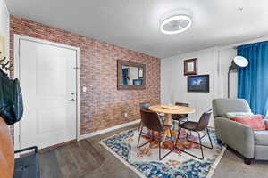 Dining room with dark hardwood / wood-style flooring, brick wall, and a textured ceiling