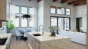 Kitchen featuring light brown cabinets, beamed ceiling, sink, a kitchen island with sink, and light wood-type flooring