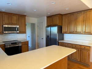 Kitchen with stainless steel appliances, decorative backsplash, and light hardwood flooring