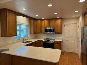 Kitchen with kitchen peninsula, light hardwood  floors, sink, and stainless steel appliances