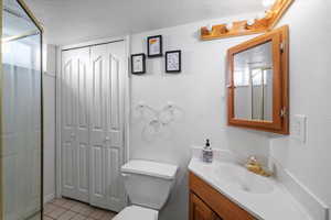 Bathroom featuring toilet, tile patterned flooring, vanity, and a textured ceiling