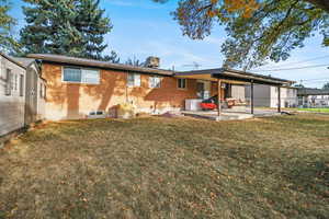 Rear view of house with a yard and a patio